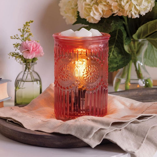Diffuseur de parfum électrique rose allumé dans une décoration d'intérieur chaleureuse.