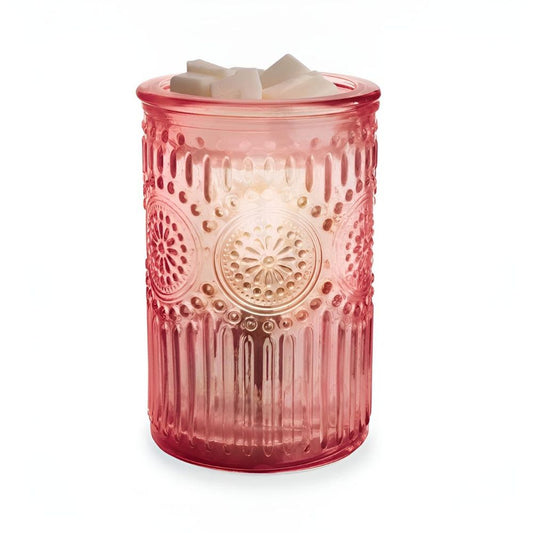 Lampe chauffe-cire électrique en verre rose avec motifs floraux en relief sur fond blanc.